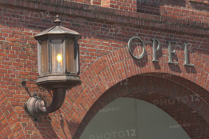 Lantern with light at main portal entrance, Adam Opel AG, inscription, on, burn, brick building, Rüsselsheim, Hesse, Germany