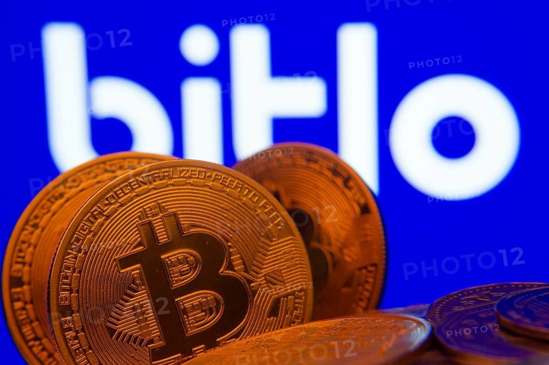 Dhaka, Bangladesh- 03 Sep 2025: Close-up of Bitcoin coins with the Bitlo logo visible on a screen in the background