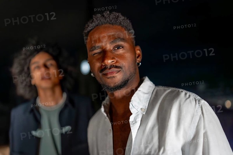 Latin man in white t-shirt looking at camera during night party in a rooftop