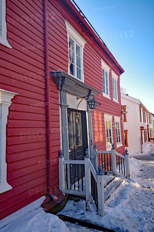 Red wooden houses along a snow-covered path under a clear sky, Røros, mining town, Unesco World Heritage Site, Tröndelag, Norway