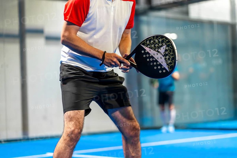 Cropped photo of the lower part of an unrecognizable mature sportive man playing paddle tennis in an indoor court