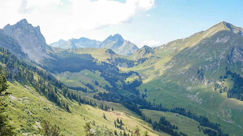 Scenic panorama of the Jaun Pass in the Swiss Alps, featuring verdant mountains and clear skies