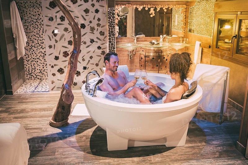 Happy interracial couple relaxed in the jacuzzi enjoying their self and drinking wine