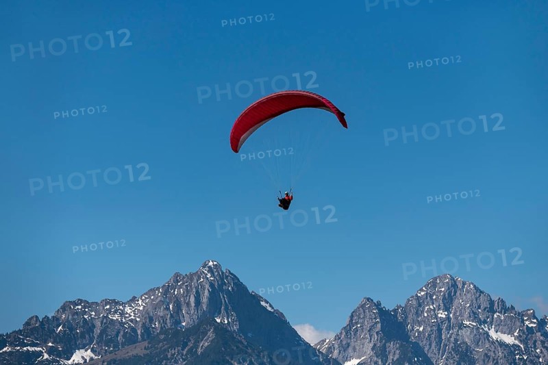Paraglider with red glider high above snow-covered mountain peaks, Schwangau near Füssen, Ostallgäu district, Swabia, Bavaria, Germany