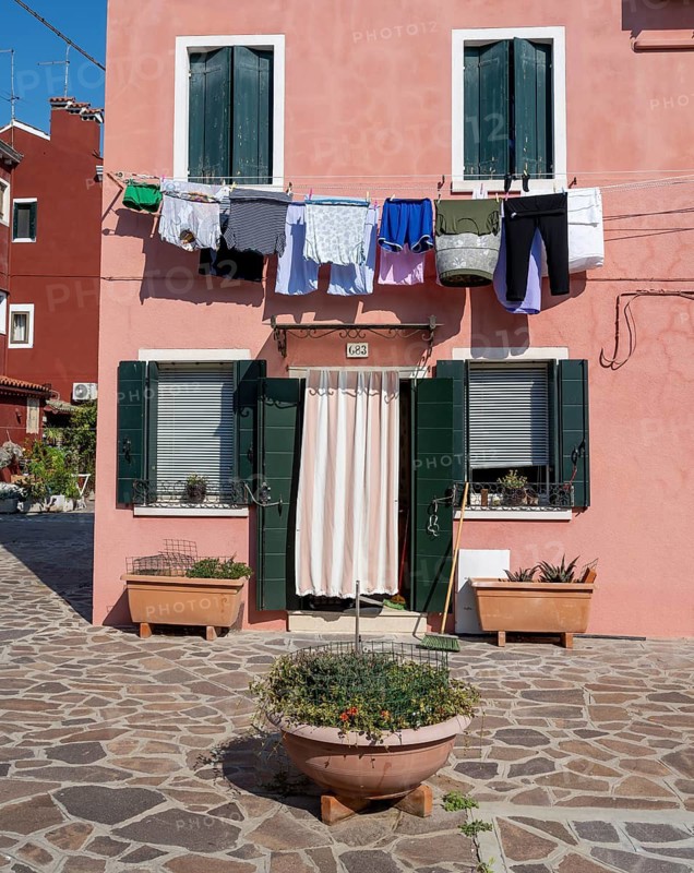 Pink house facade with clothesline, windows and front door, colourful houses, alleys on the island of Burano, Venice, Veneto, Italy