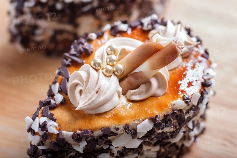 Cakes with chocolate chips and cream decorations on wooden board on white background. selective focus, close up