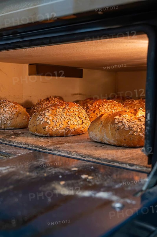 Several golden brown breads with oats are baked in the warm light of an oven, bake bread, Haselstaller Hof, Gechingen, Calw district, Germany
