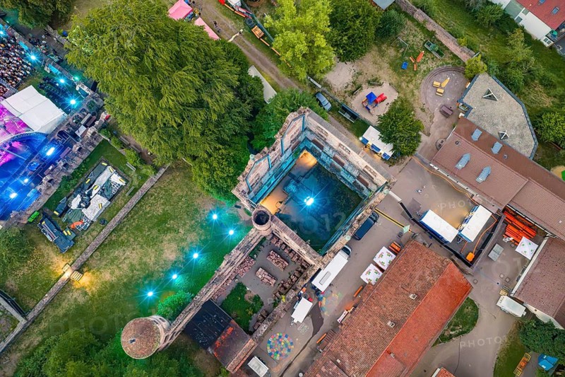 View from above of ruins and a festival with lighting effects and surrounded by green trees, Calwer Klostersommer Festival, Hirsau Abbey, Calw, Black Forest, Germany