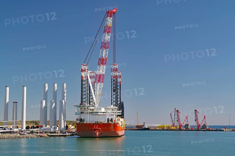 A large crane in the harbor with several ships and clear blue sky in the background, Windkraft, Rönne, Bornholm, Denmark