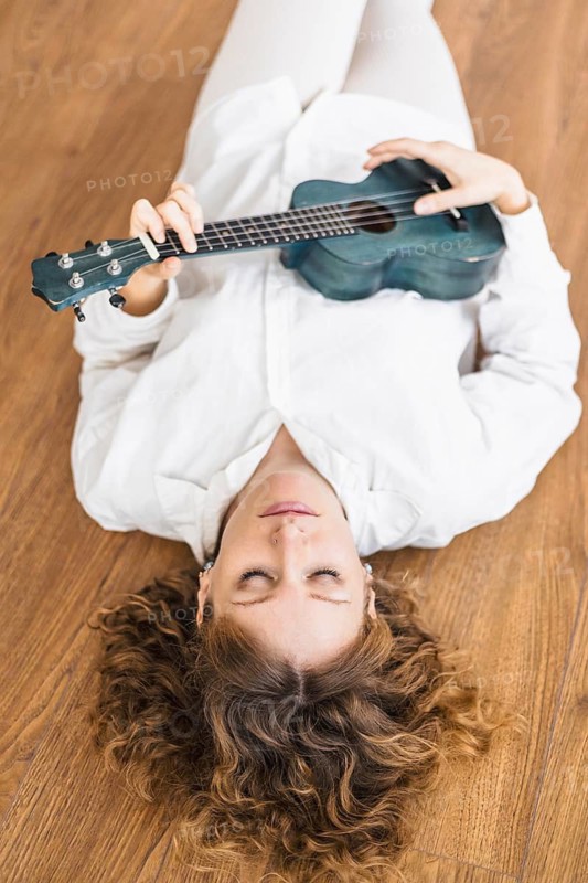 Person lying on the floor with a ukulele, exuding a sense of calmness