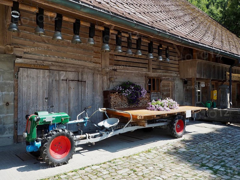 Rapid single-axle tractor and wagon in front of a rustic wooden hut with flower decoration, Kemmeriboden Bad, UNESCO Biosphere Entlebuch, Switzerland