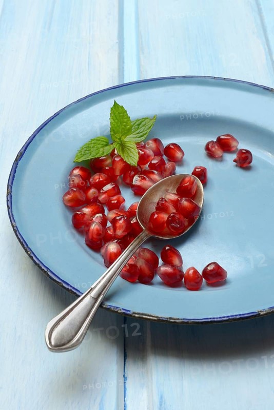 Pomegranate seeds and spoons on plate, Punica granatum