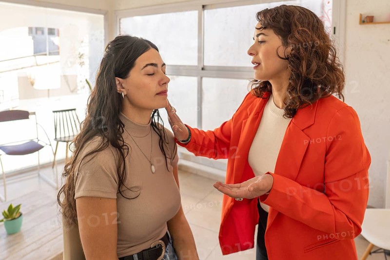 Professional makeup artist gently touching a client's face while assessing skin condition before beginning makeup application