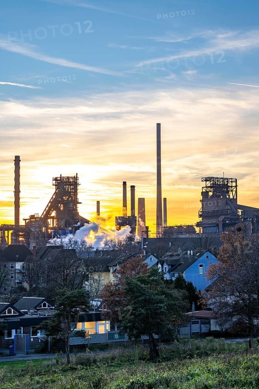 Blast furnace Schwelgern 1, Black Giant, Schwelgern 2 ThyssenKrupp Steel plant Schwelgern in Duisburg-Marxloh is part of the Bruckhausen steelworks, residential buildings in the Marxloh district, sunset, North Rhine-Westphalia, Germany