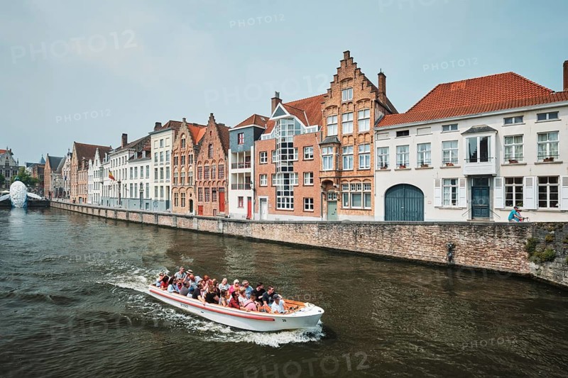 BRUGES, BELGIUM, MAY 29, 2018: Tourist boat in canal between old houses with The Bruges Whale plastic installation, Brugge Bruges, Belgium