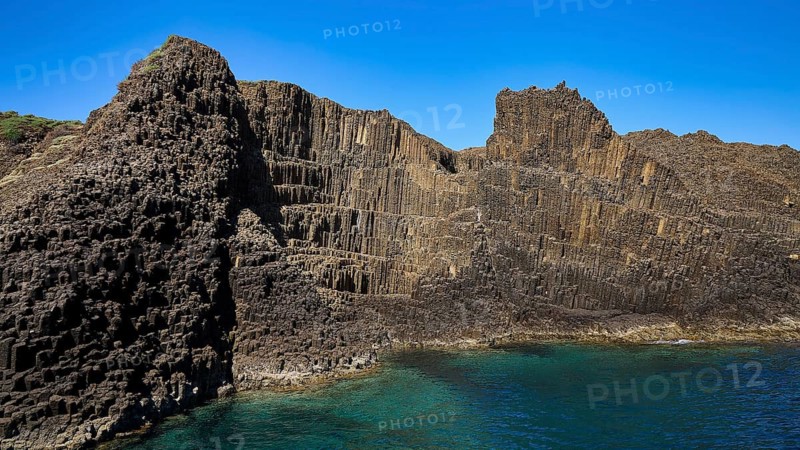 Wide rock wall with geological patterns merging into the sea, Glaronisia, Glaronesia, Milos, islets, hexagonal basalt columns, north of Milos, destination by boat, Cyclades, Greek Islands, Greece