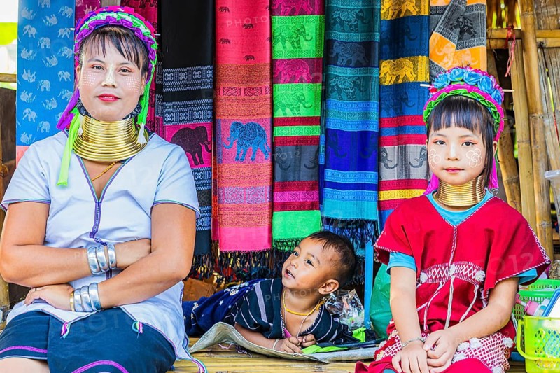Young woman with children from the Karen minority group wearing brass rings around her neck, colorful traditional headdresses and clothing, Karen Long Neck Village, Chiang Mai, Thailand