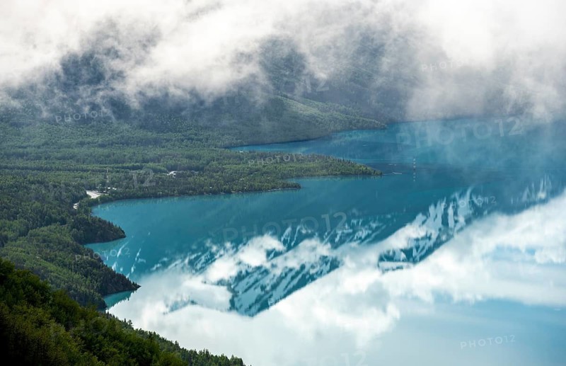 View of snowy mountains in spring and turquoise Kenai Lake with reflection, Slaughter Ridge Trail, Cooper Landing, Kenai Peninsula, Alaska, USA