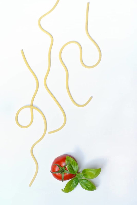 Individual spaghetti and tomato with basil, concept image