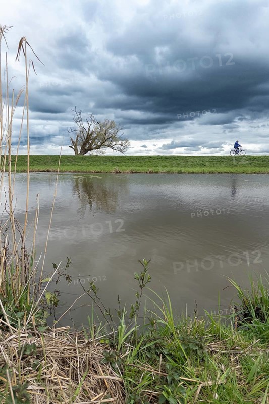 Cyclists in stormy winter atmosphere on the dam on the Hunte am Dümmer See, Hüde