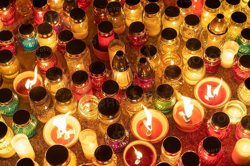 Colorful candle jars glowing warmly in the night. A huge number of multicolored burning candles and lamps at a cemetery during All Saints' Day celebrations. Warsaw, Poland