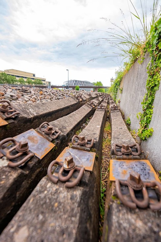 Close-up of rusty railroad ties and gravel next to a wall, Leonhard Weiß electrification station conversion, Waldshut. germany