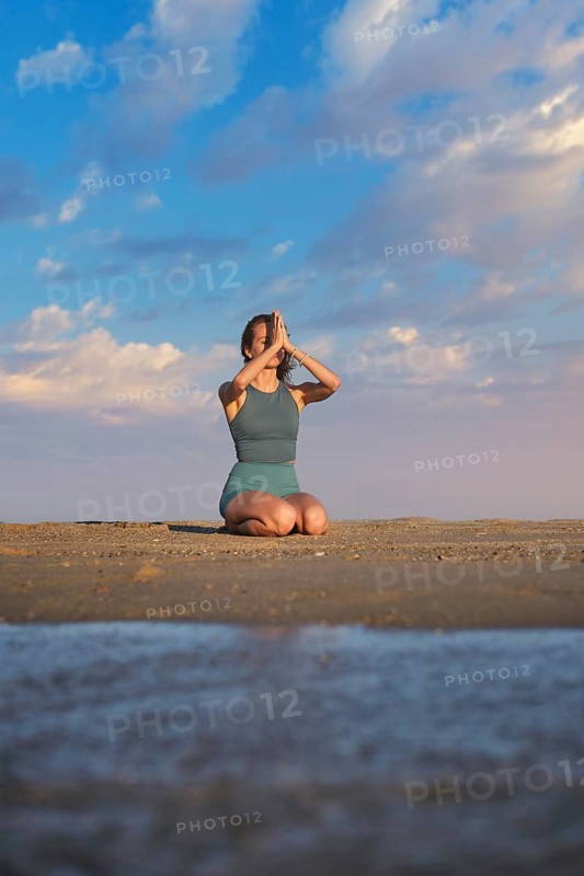 Beach scene featuring yoga, a young woman, vajrasana, thunderbolt pose, a woman, and kneeling