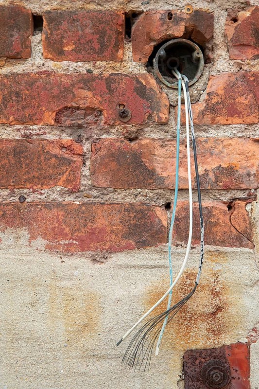 Detroit, Michigan - Unconnected electrical wires emerging from a pipe outside an old industrial building