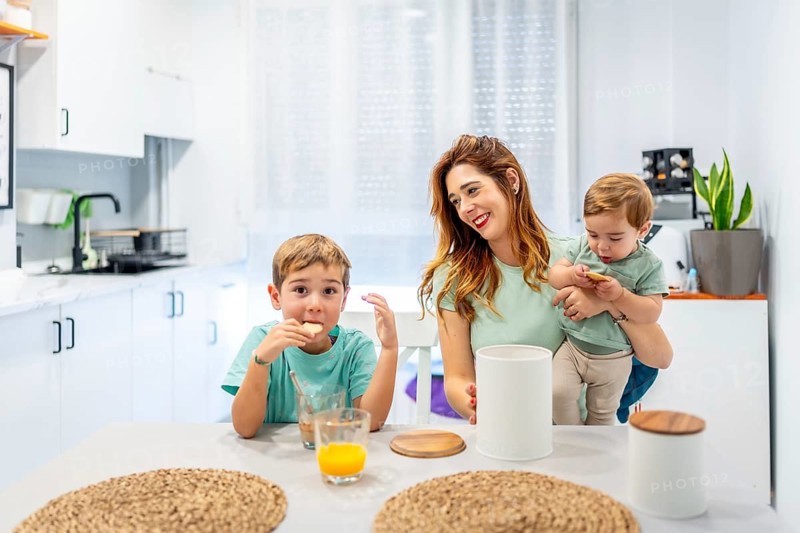 Happy family of three having breakfast sitting on the kitchen at home before school