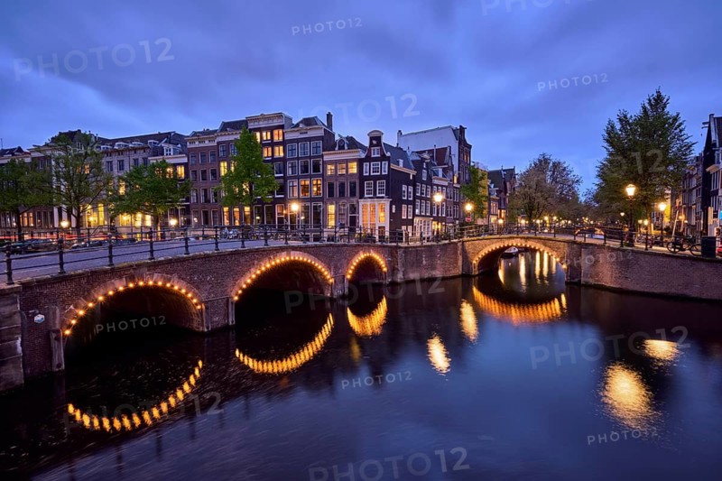 Night view of Amterdam cityscape with canal, bridge and medieval houses in the evening twilight illuminated. Amsterdam, Netherlands