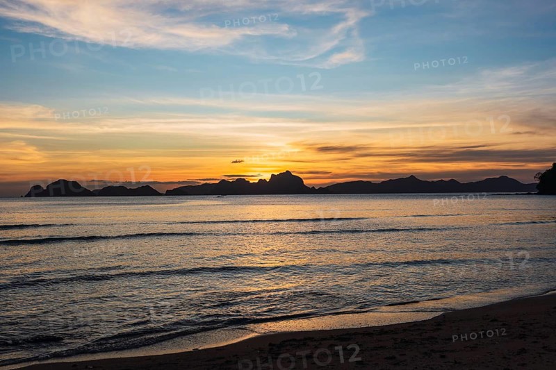 A breathtaking sunset over a serene sea in the Philippines, highlighting the silhouette of islands against vibrant sky hues. Perfect for travel and nature themes