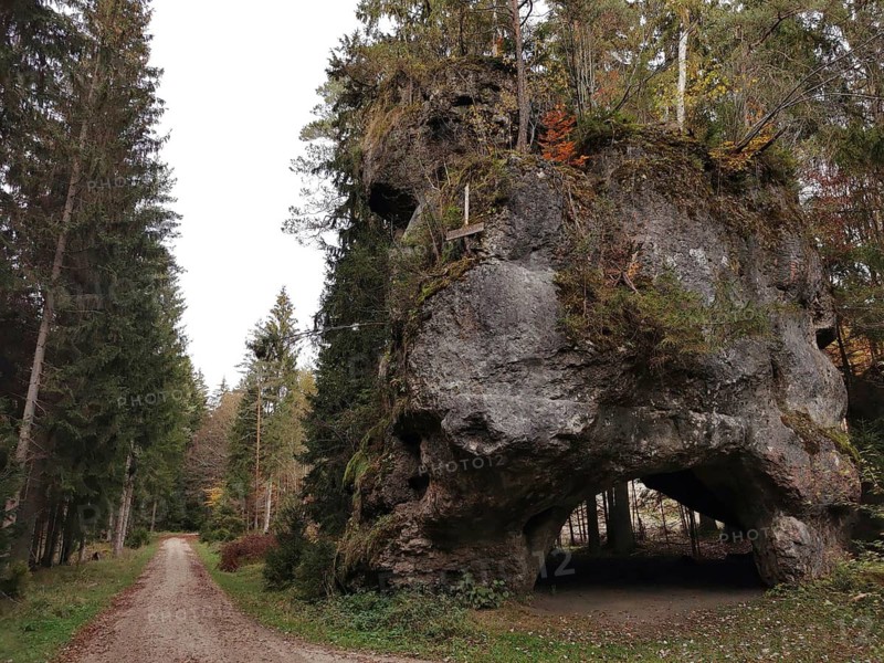 Massive rock in a wooded area flanked by tall conifers next to a path, Großer Lochstein, Veldensteiner Forst, Germany