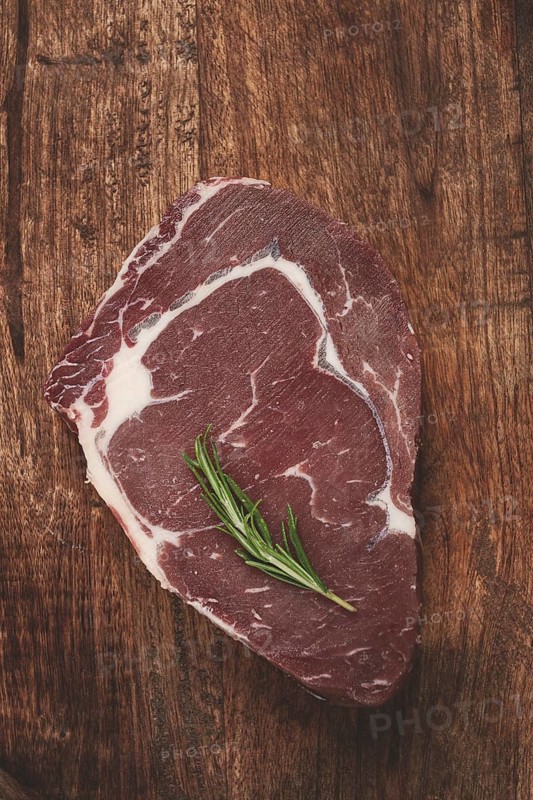 Raw steak, beef steak, rib eye steak, on a cutting board, freshly frozen, with spices and herbs, on the table, top view