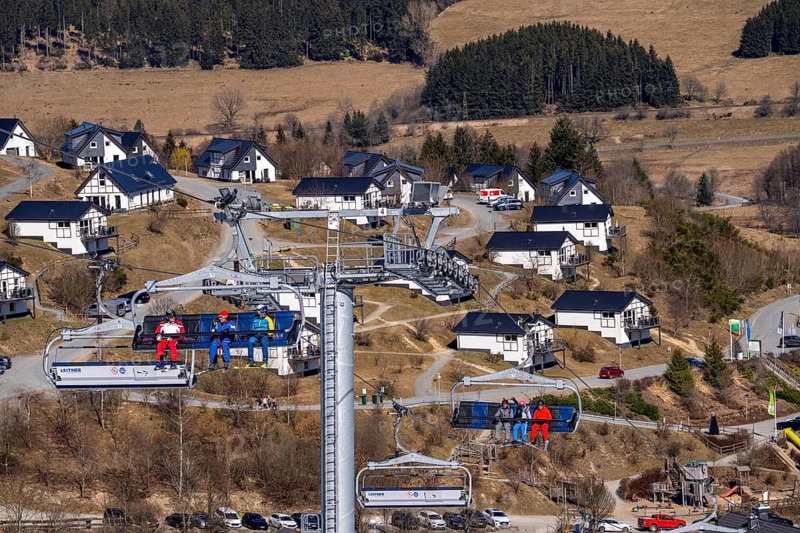 Winter sports area in the Sauerland, Winterberg ski lift carousel, artificial snow slopes, artificial snow from over 360 snow guns, Poppenberg ski area, background holiday homes at Landal Ferienpark Winterberg, 12 of 24 lifts are in operation in mid-March, the rest of the landscape is snow-free, North Rhine-Westphalia, Germany