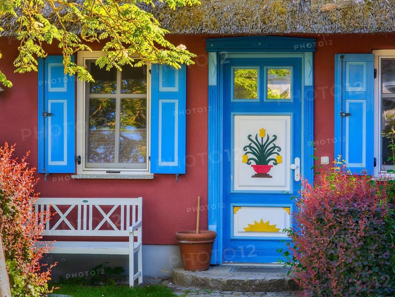 Thatched-roof house with colorful door and window and bench Baltic Sea Germany