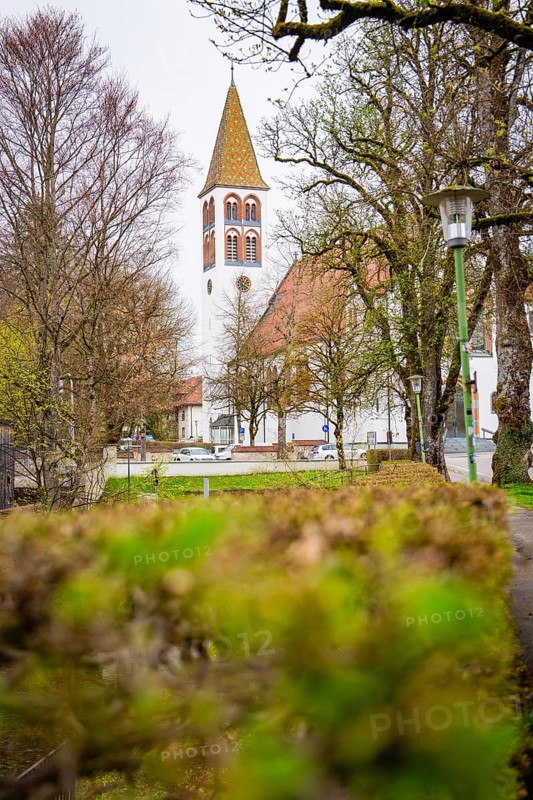 White church tower juts out between early spring trees in an old town, Isny, Allgäu, Bavaria, Germany