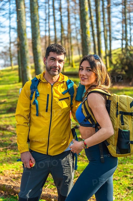 Hikers with backpacks walking through a vibrant forest, soaking in the beauty of nature on a sunny day, enjoying their adventure together