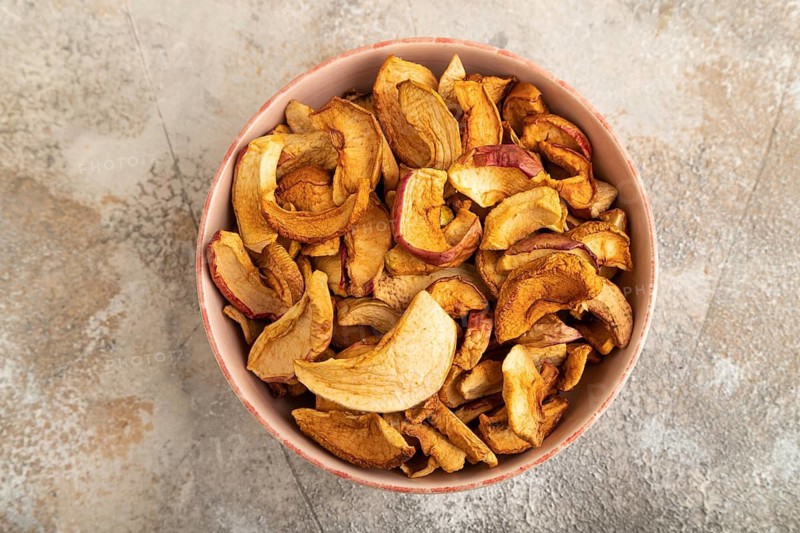 Dried Apples in ceramic bowl on brown concrete background. Top view, close up, flat lay. healthy food, minimalism. sweet