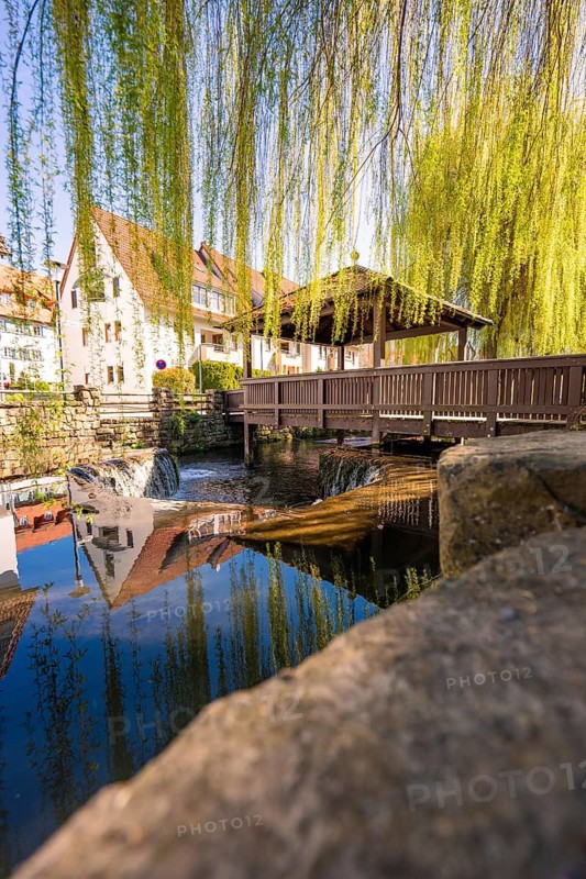 A picturesque bridge scene with reflections in the water, framed by green pastures in an idyllic setting, Aidlingen, Böblingen district, Germany