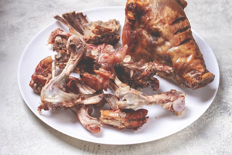 Roast pork head, with remnants of bones and meat, on a white platter, no people, close-up