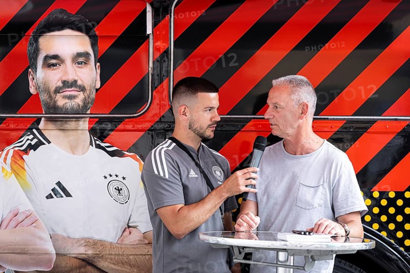 Former Bundesliga player and German international Ralf Falkenmayer is interviewed about EURO 2024 in Frankfurt's Fan Zone. Falkenmayer played a total of 385 games in the Bundesliga for Eintracht Frankfurt and Bayer 04 Leverkusen from 1981 to 1996, scoring 37 goals. He won the DFB Cup with Eintracht in the 1980-81 season and the UEFA Cup with Bayer Leverkusen in the 1987-88 season. He played four international matches for the national team from 1984 to 1986