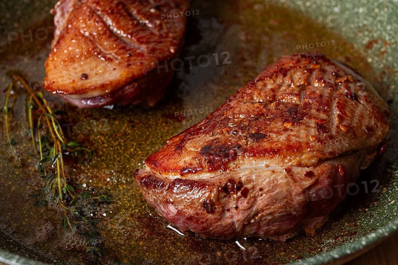 Cooking duck breast, in a frying pan, fried, with spices and herbs, close-up, no people