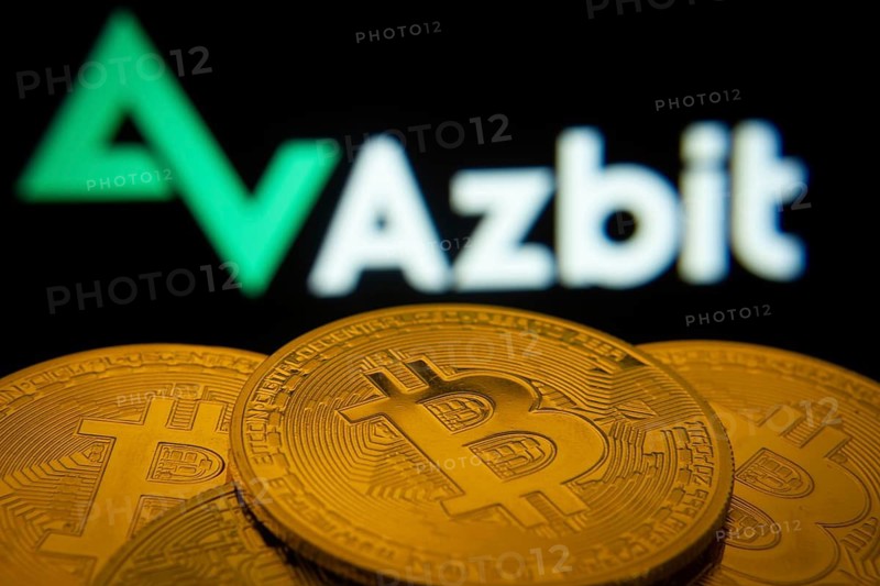 Dhaka, Bangladesh- 02 June 2025: Close-up of Bitcoin coins with the Azbit logo visible on a screen in the background