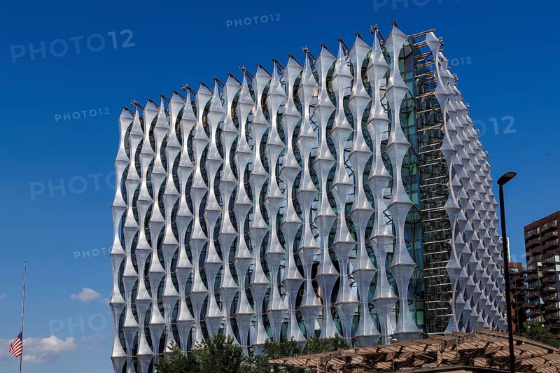 The faceted ETFE clad lattice of the United States Embassy forms a crystalline cube above a colonnade at Nine Elms, designed by Kieran Timberlake and opened in 2017 to replace the long standing Grosvenor Square embassy, with the American flag flying before its glass and stone walls. London, England, United Kingdom