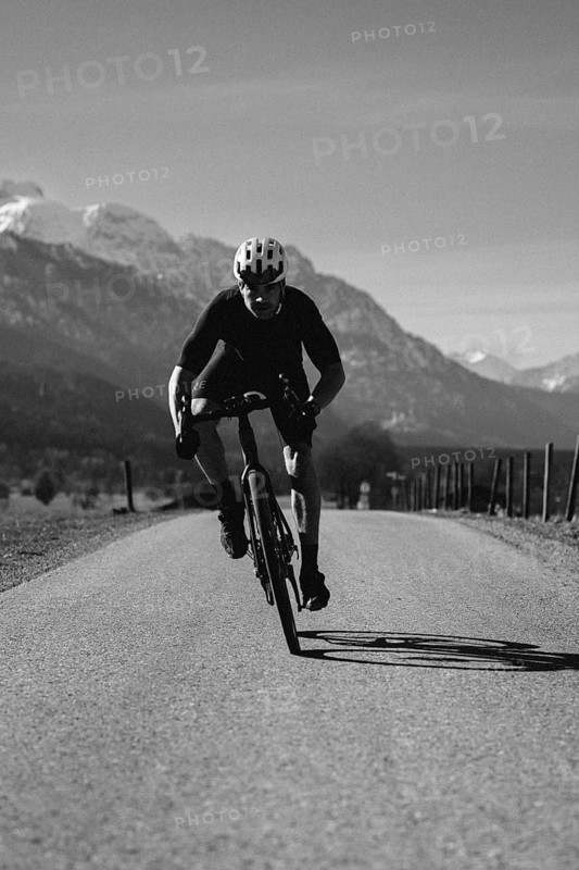 Road bike rider in spring near Halblech in the Allgäu in front of a picturesque backdrop of the Alps, Bavaria, Germany