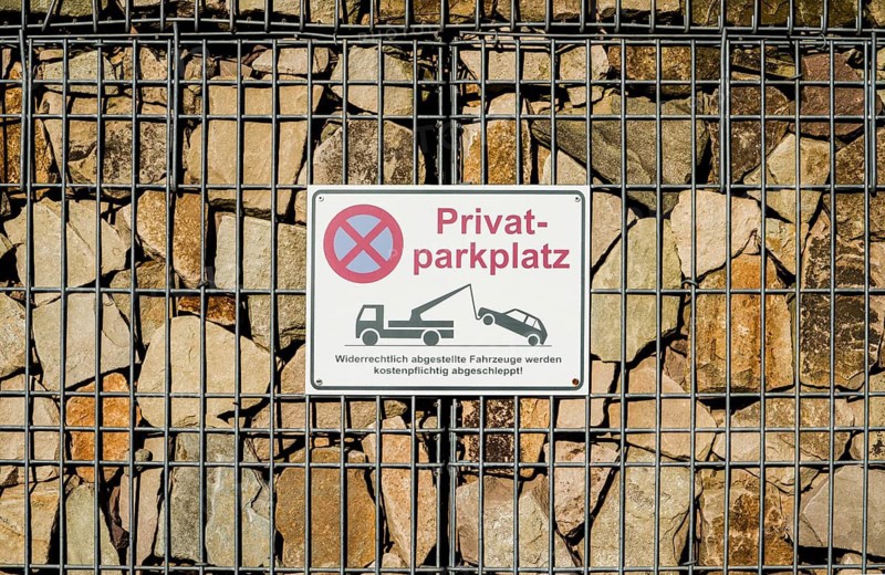 Sign on a gabion filled with stones, German for private car parking, Germany