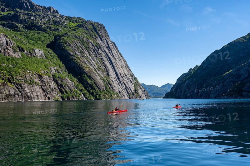 Two kayakers with red kayaks in the fjord Trollfjord, mountains reflected in the water, fjord landscape and mountains, Lofoten, Nordland, Norway