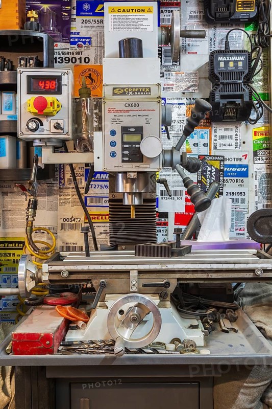 Craftex CX600 Series milling and drilling machine plus posted instruction pages on wall inside cluttered home garage workshop, Quebec, Canada