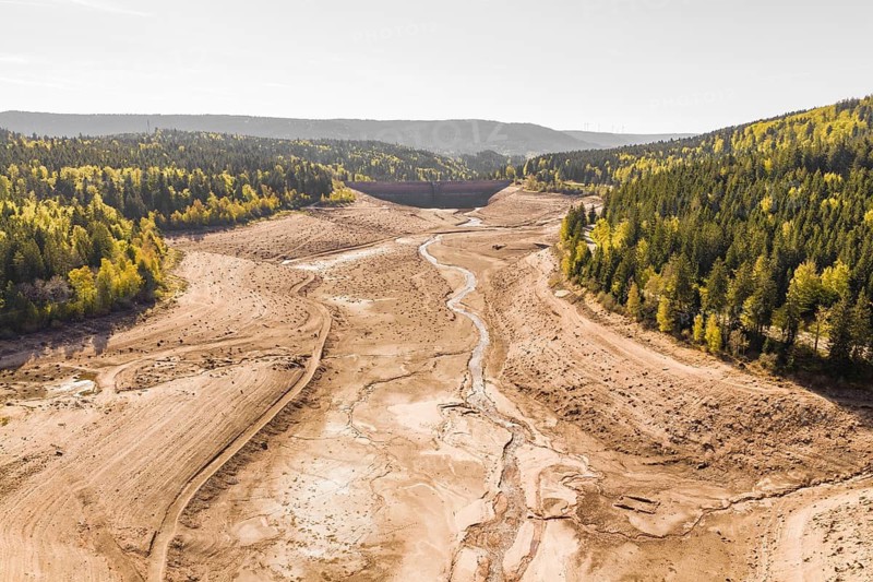 Extensive dry riverbed with surrounding forests and autumnal hills, emptied Schwarzenbach dam, Forbach, Black Forest, Germany