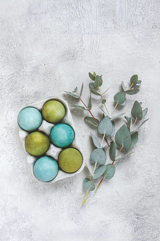 Easter colored eggs, in green and turquoise tones, with eucalyptus leaves, Easter card, top view, no people